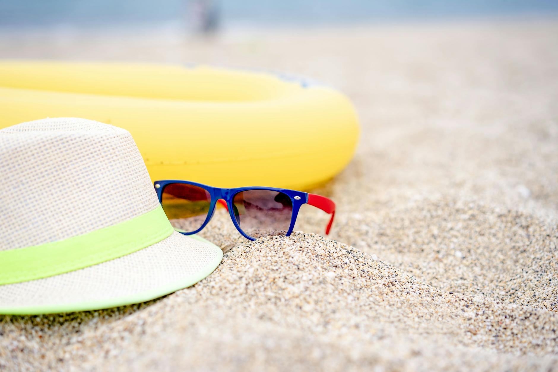 a hat and sunglasses on a beach